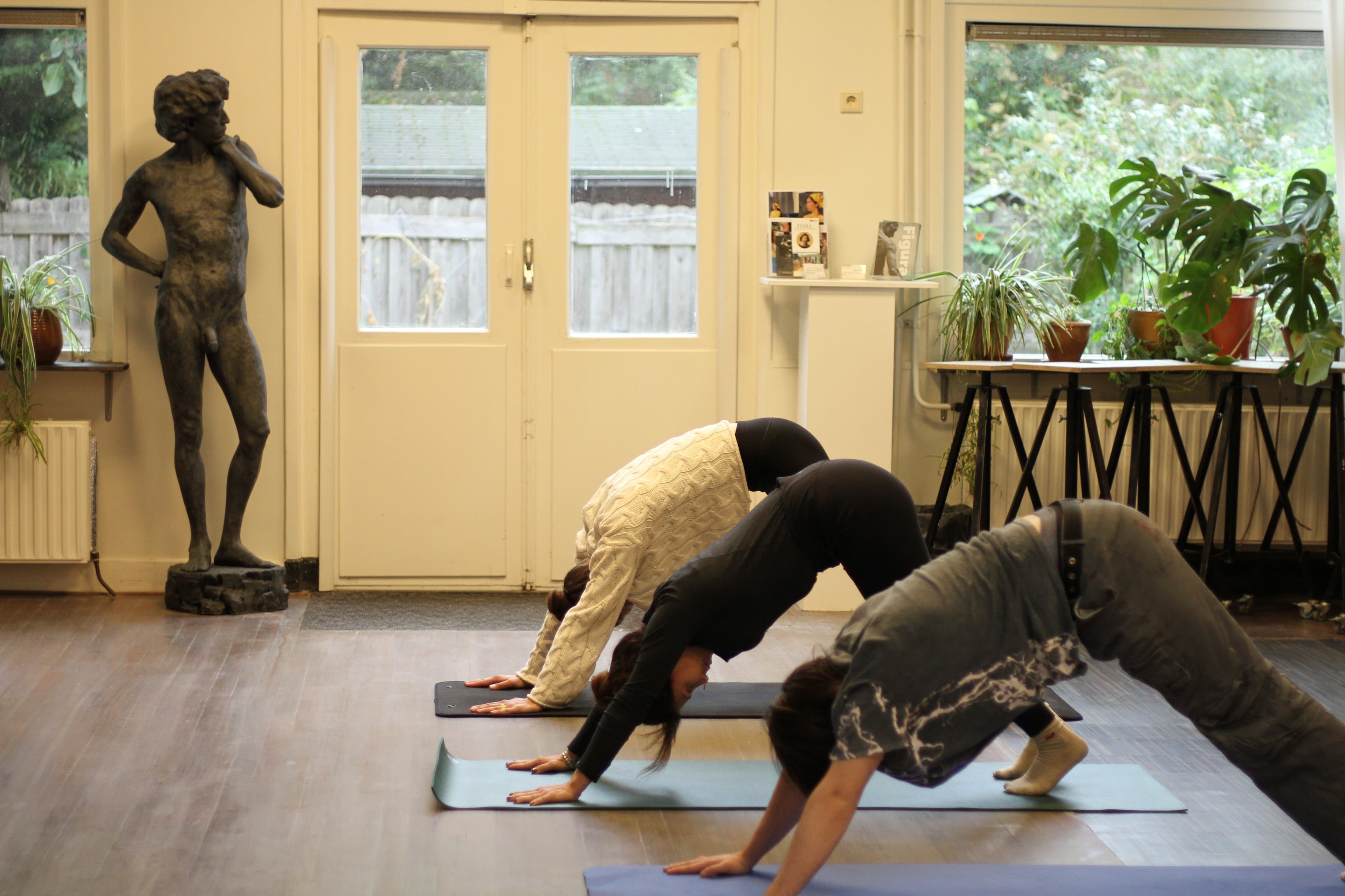A small group practising yoga on mats beside a sculpture, at Figura in Amsterdam