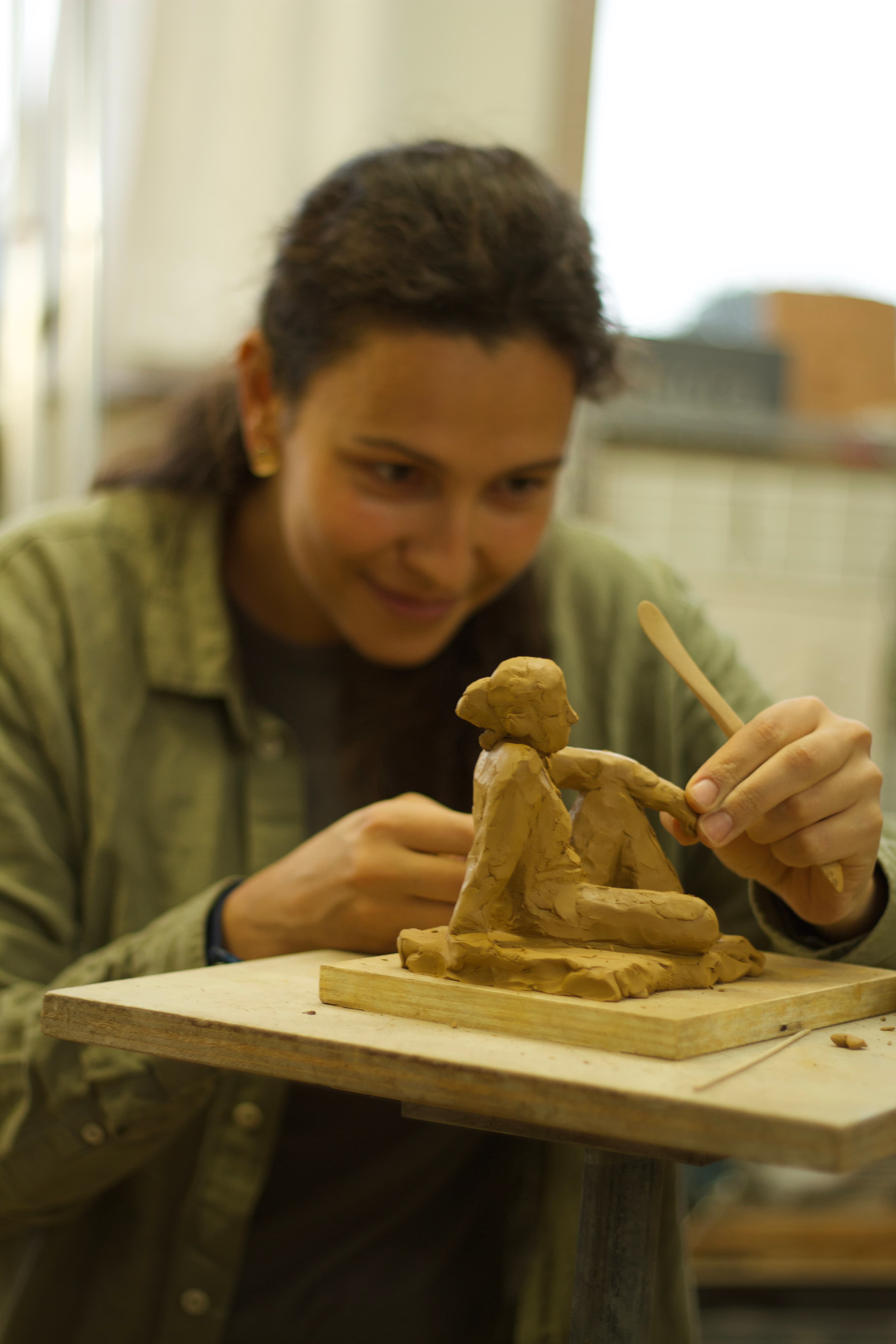 Daria shaping a small clay figure during a sculpting session